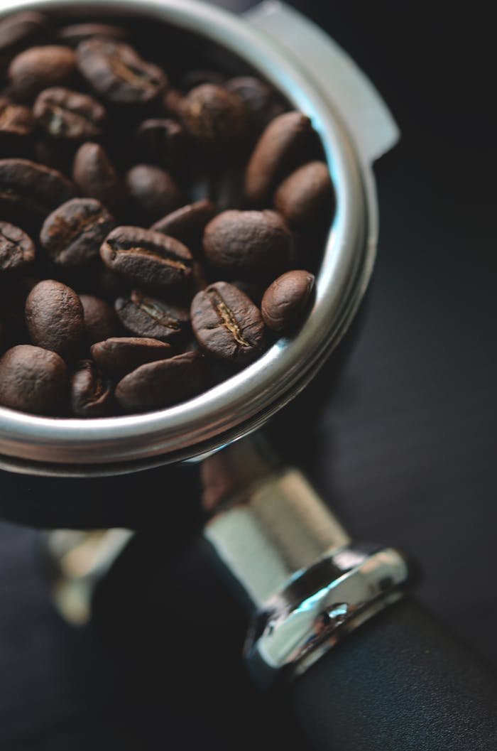 Aromatic coffee beans resting in a metal portafilter, ready for brewing.